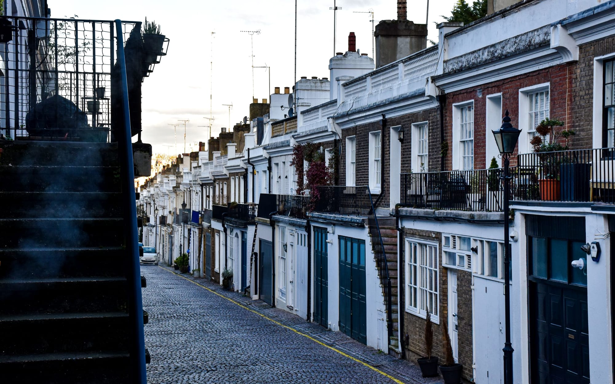 A quiet Chelsea side street of brick townhouses in soft evening light