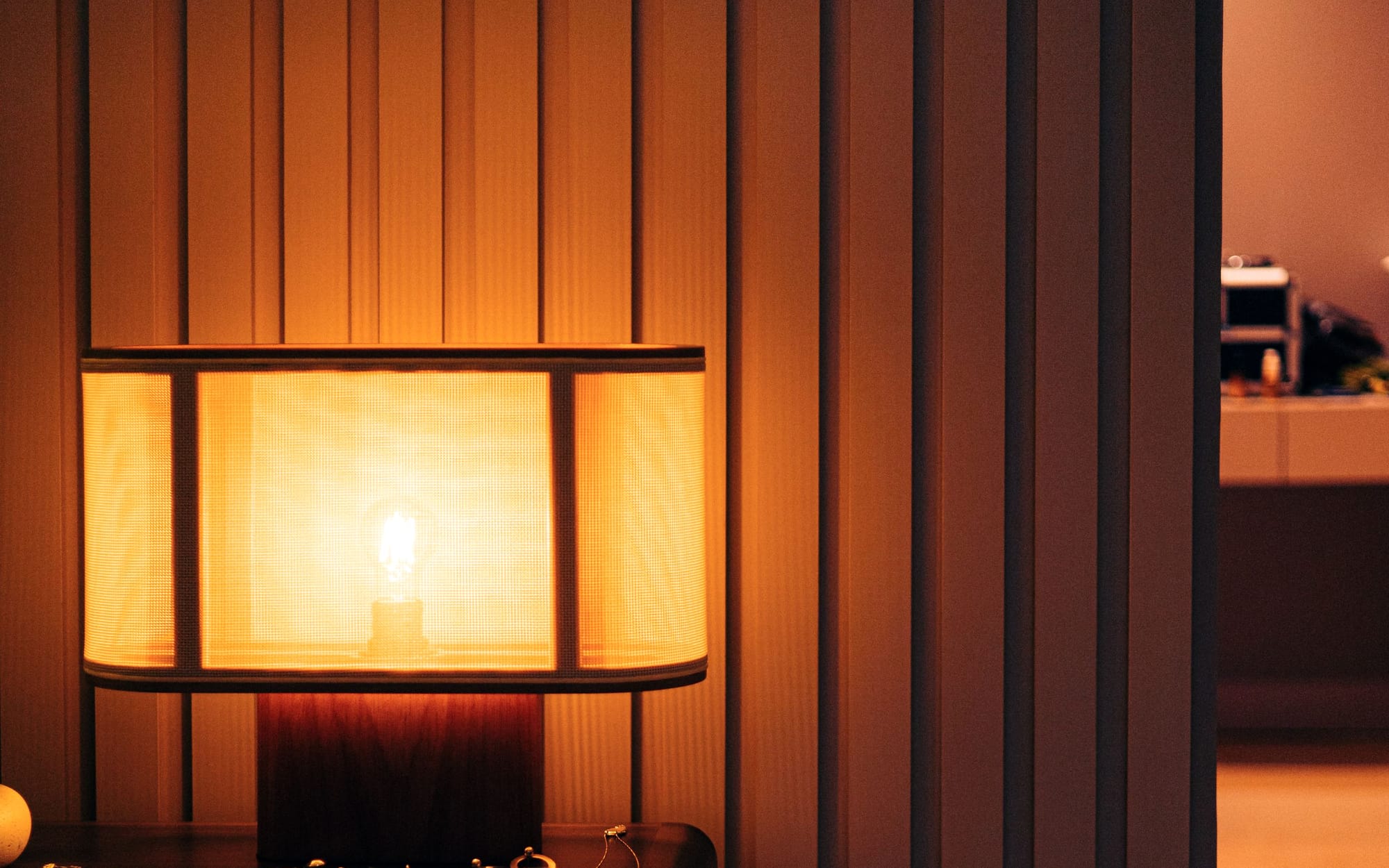 A quiet hotel room in low evening light with a made bed and a chair by the window