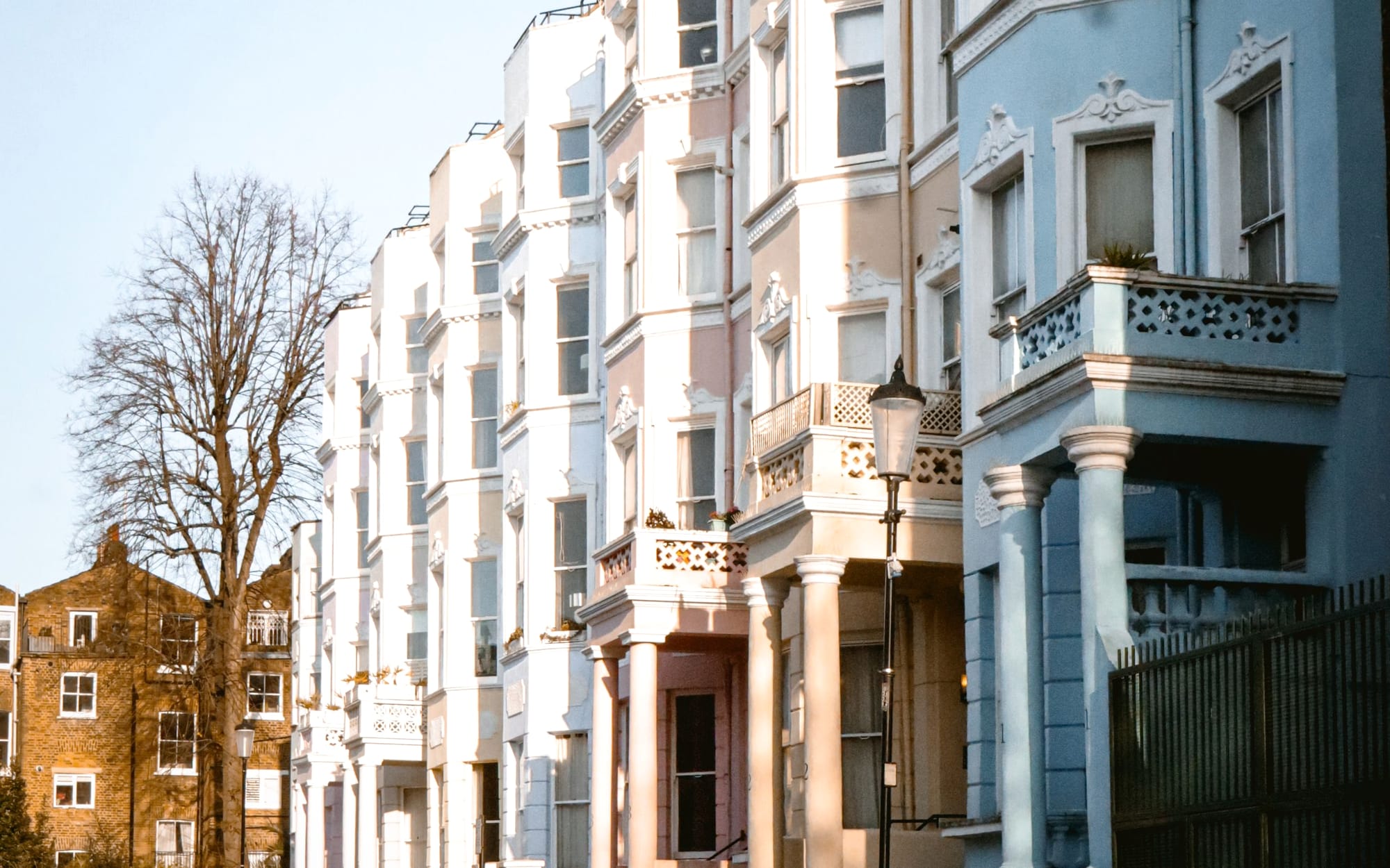 A row of pastel-painted terraced houses on a Notting Hill street