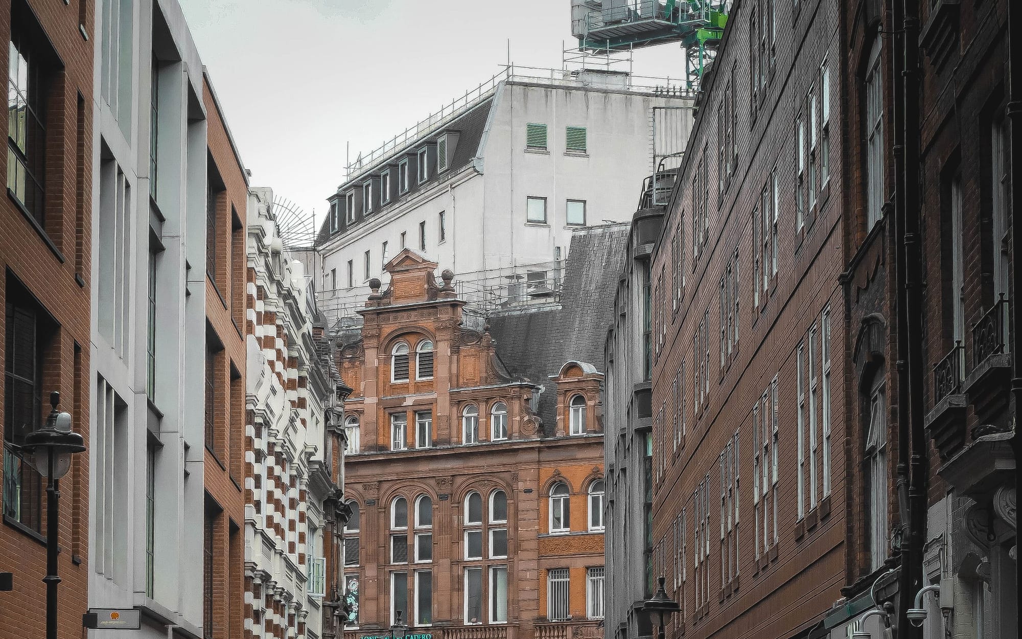 A narrow Soho street of Georgian buildings with shopfronts and pedestrians