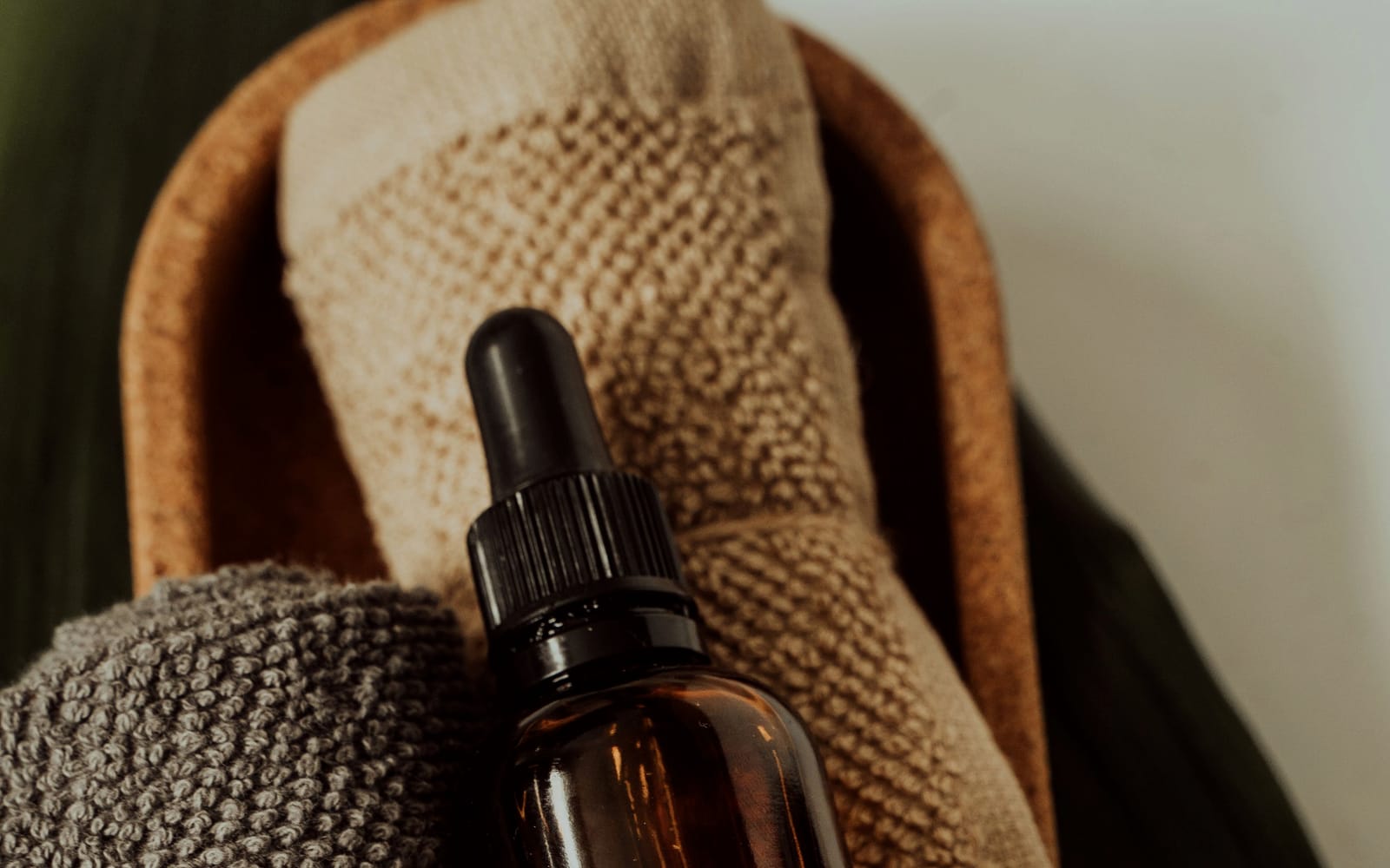 A small bowl of massage oil and a folded towel on a table by a window