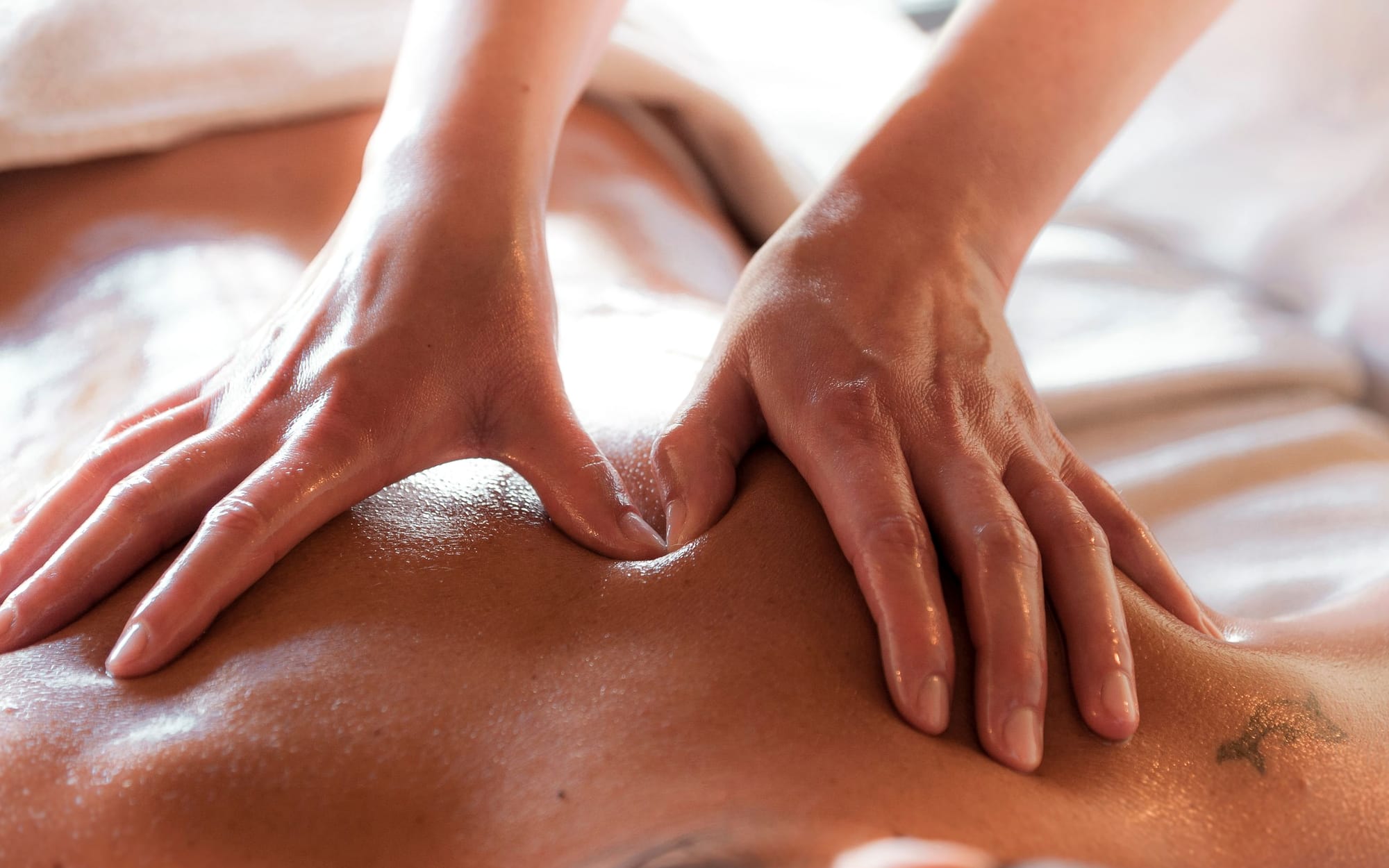 A long, even forearm stroke drawn down the full length of a client's back